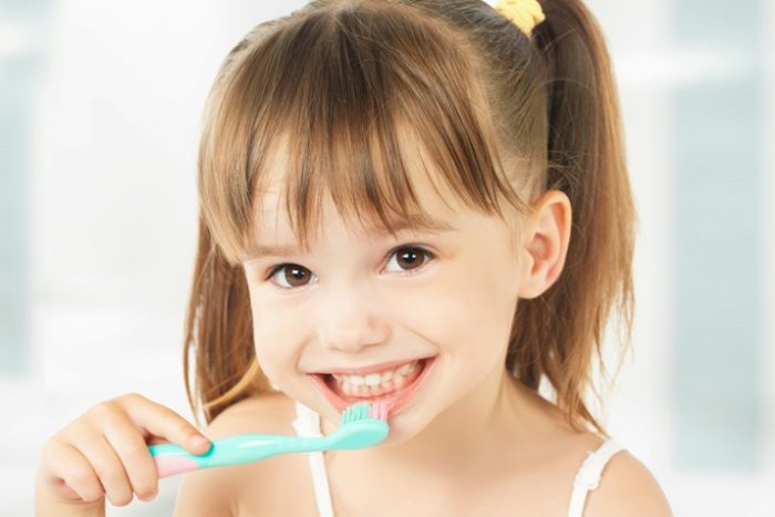 niña con cepillo de dientes