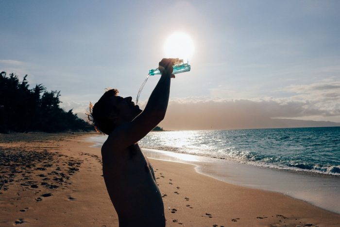 Hombre tomando agua en una playa