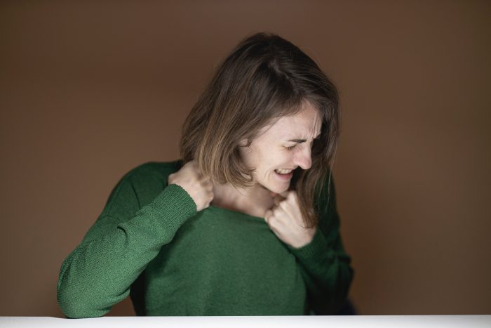 Mujer estira ropa sweater con gesto dolor molestia