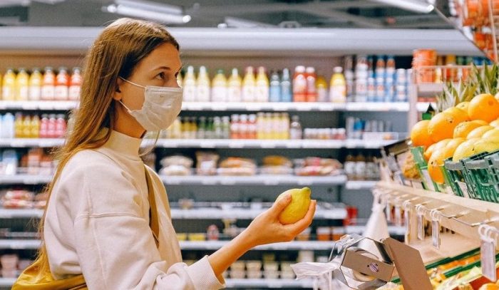 mujer con barbijo comprando alimentos durante la pandermia