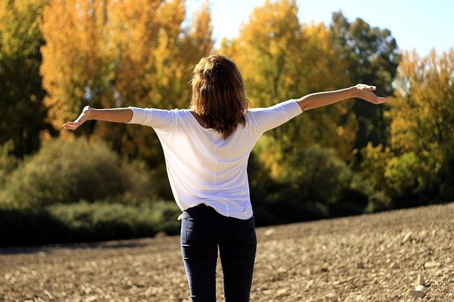 mujer con brazos abiertos al aire libre