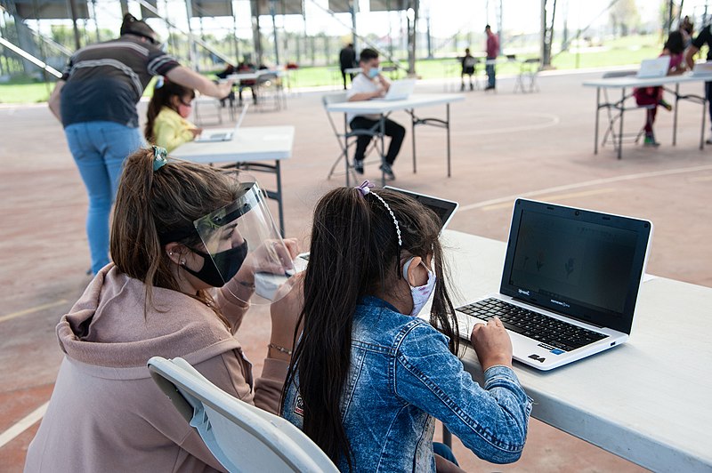 clase de computación al aire libre maestra y alumna con máscara