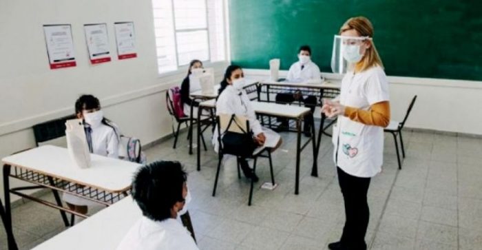 clase presencial en escuela maestra niños distancia