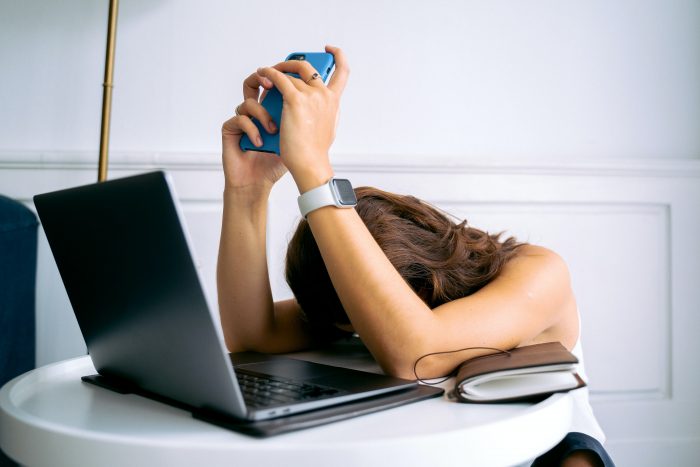 mujer cansada con computadora y celular
